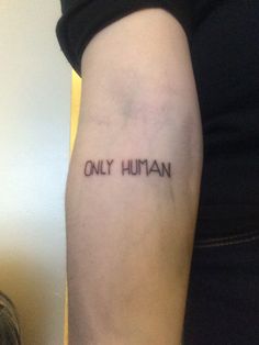 a woman's arm with the words only human tattooed in black ink on it