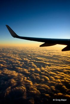 an airplane wing above the clouds at sunset