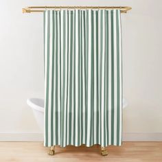 a green and white striped shower curtain hanging from a gold metal rod on a wooden floor