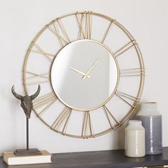 a gold clock sitting on top of a wooden shelf next to a vase and cow head