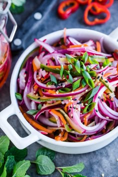 a white bowl filled with sliced red onions and green peppers on top of a table