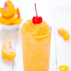 an orange drink with a cherry on the top sits in front of some candies