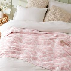 a bed with white pillows and pink blanket