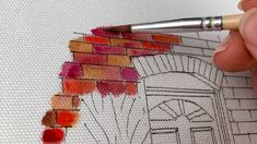 a person is drawing with colored pencils on paper and has a brick wall in the background