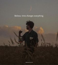 a man standing in tall grass holding a lantern with the words believe, time changes everything