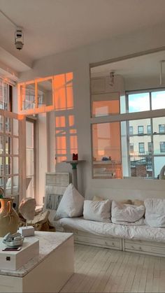 a living room filled with white furniture and lots of window panes on the wall