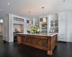 a large kitchen with an island in the center and white cabinets on both sides, along with wooden floors