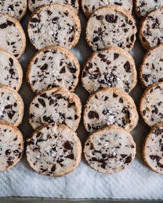 chocolate chip cookies are arranged on a piece of parchment paper and lined up in rows