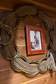 a roped wreath is hanging on the wall next to a framed photo with a cowboy image