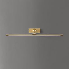 a bathroom light that is on the wall in front of a gray wall with a gold handle