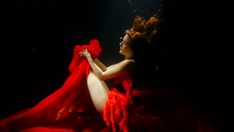 a woman in a red dress under water