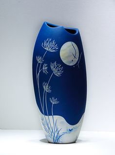 a blue vase sitting on top of a white table next to a plant and moon