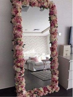 a mirror that has flowers on it in front of a room with a white couch