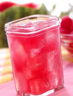 a glass jar filled with liquid sitting on top of a table next to bowls of strawberries