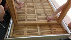 two people are working on a wooden bed frame