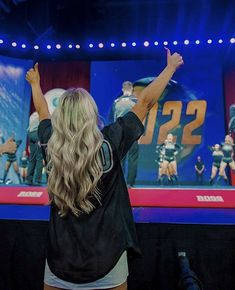 a woman standing in front of a screen with her hands up