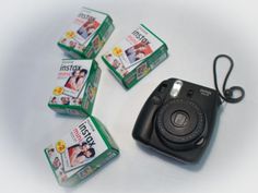 a black camera sitting on top of a table next to four small packages of film