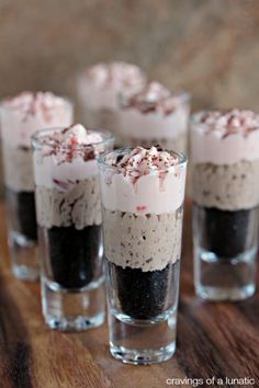 four glasses filled with dessert on top of a wooden table