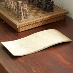 a wooden chess board sitting on top of a table next to a piece of wood