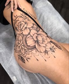 a woman's thigh with flowers on it and an arrow tattoo in the middle