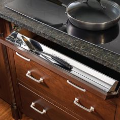 a pan is sitting on top of a drawer in front of a stove with utensils