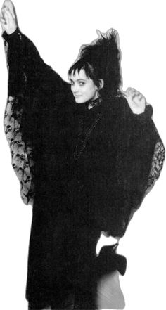 a woman in black is posing with her arms up and hands behind her back,