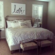 a white bed sitting in a bedroom next to two windows