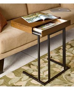 a small table with a magazine on it in front of a couch and coffee table