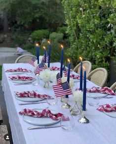 an outdoor table set with american flags and candles