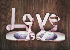 a pair of ballet shoes sitting on top of a wooden floor next to the word love