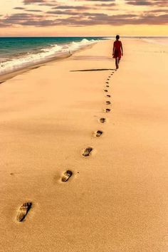 a person walking on the beach with footprints in the sand