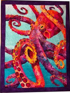 an octopus quilted on top of a blue and purple wall hanging from a wooden frame