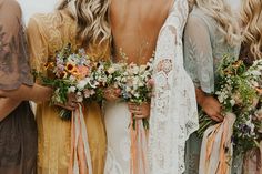 a group of women standing next to each other wearing dresses and holding bouquets in their hands