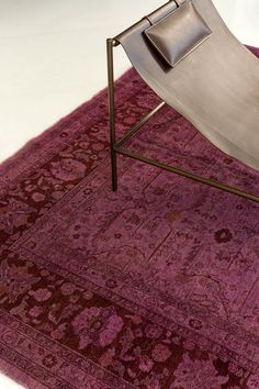 a chair sitting on top of a purple rug next to a metal stand with a pillow