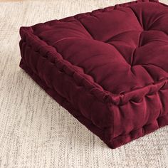 a red square dog bed sitting on top of a rug