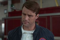 a man wearing a fire fighter's uniform standing in front of a fire truck