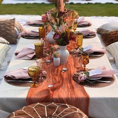 the table is set with pink napkins and place settings for an outdoor dinner party