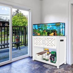 a fish tank sitting on top of a white cabinet next to a sliding glass door