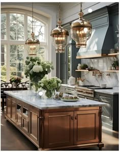 a kitchen island with marble counter tops and gold pendant lights hanging from it's ceiling