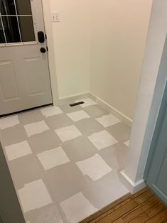 an empty room with white walls and wood flooring on the ground, in front of a door