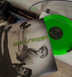 a green vinyl record sitting on top of a wooden table next to a cd player