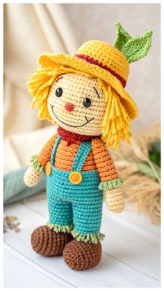 a crocheted doll is wearing overalls and a hat with an orange nose