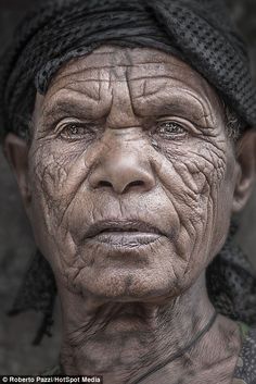 an old woman with wrinkles on her face and neck is looking at the camera