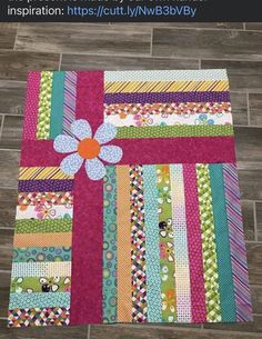 a colorful quilt on the floor with an applique flower