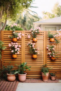 several potted plants are hanging on a wooden fence with flowers in the middle and behind them