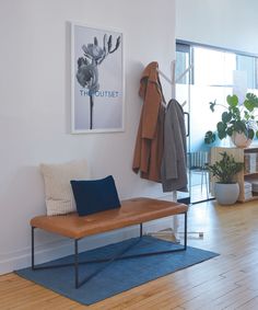 a room with a bench, coat rack and potted plants