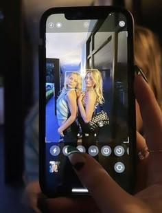 a person holding up a cell phone with two women on the screen in front of them