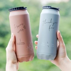 two women holding up pink and blue water bottles with writing on them that say thank you for