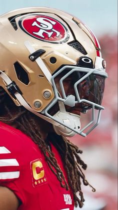 a close up of a football player wearing a helmet with dreadlocks on his head