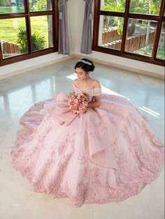 a woman in a pink dress is sitting on the floor with her bouquet and smiling